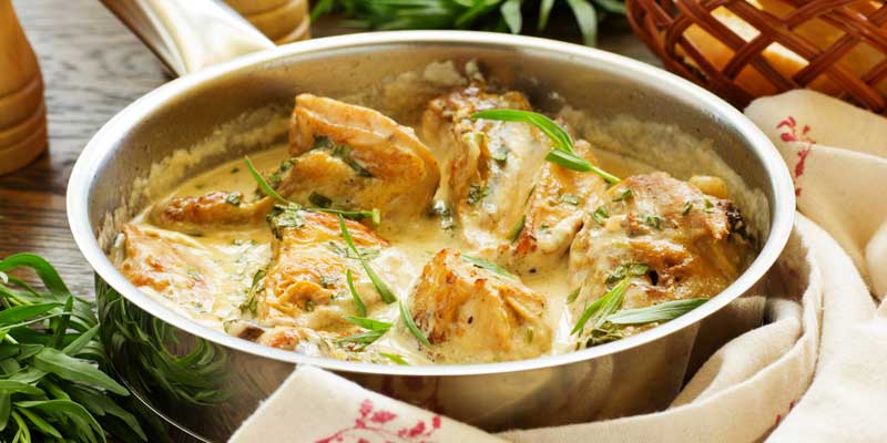 chicken in a pot with tarragon leaves