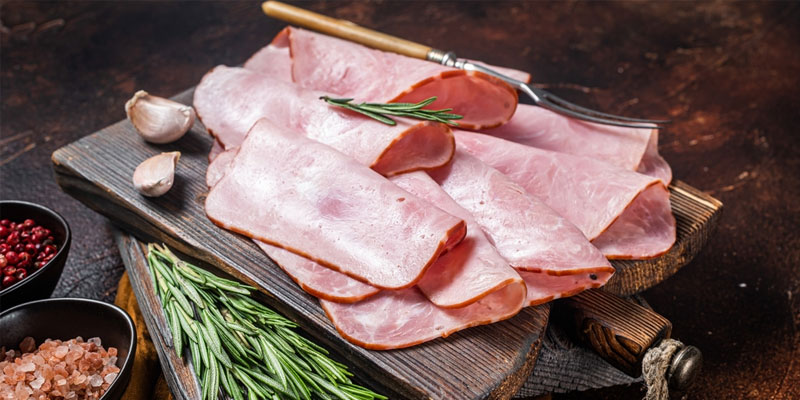 thin slices of ham on wooden cutting board