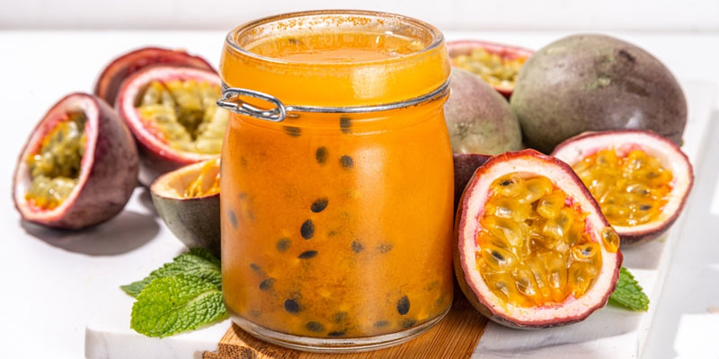 collected passion fruit in a mason jar with sliced fruit in the background.