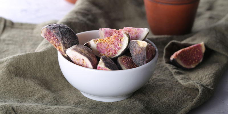 freeze dried figs in a white bowl with cloth background