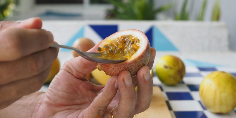 scooping out passion fruit flesh using a spoon